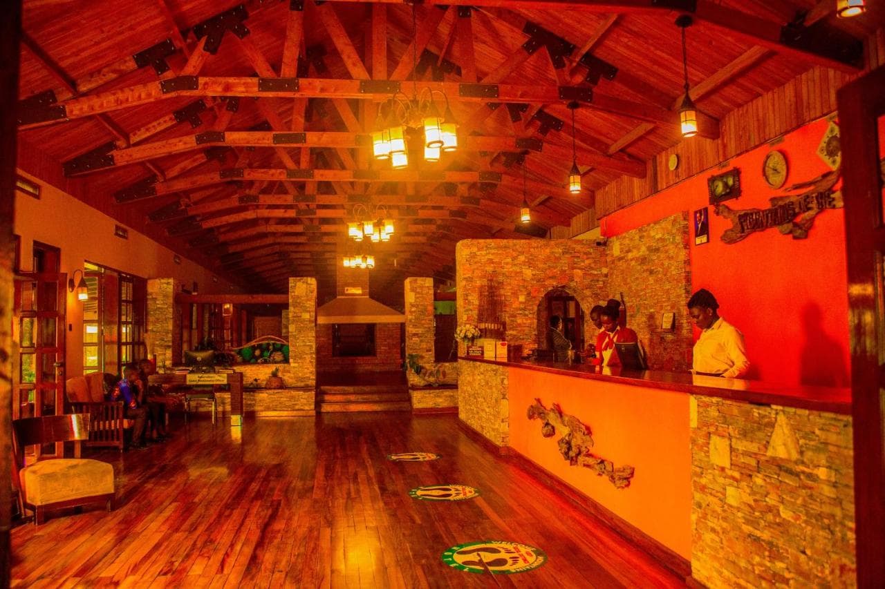 Warm-lit lodge reception lounge with timber beams and a stone counter