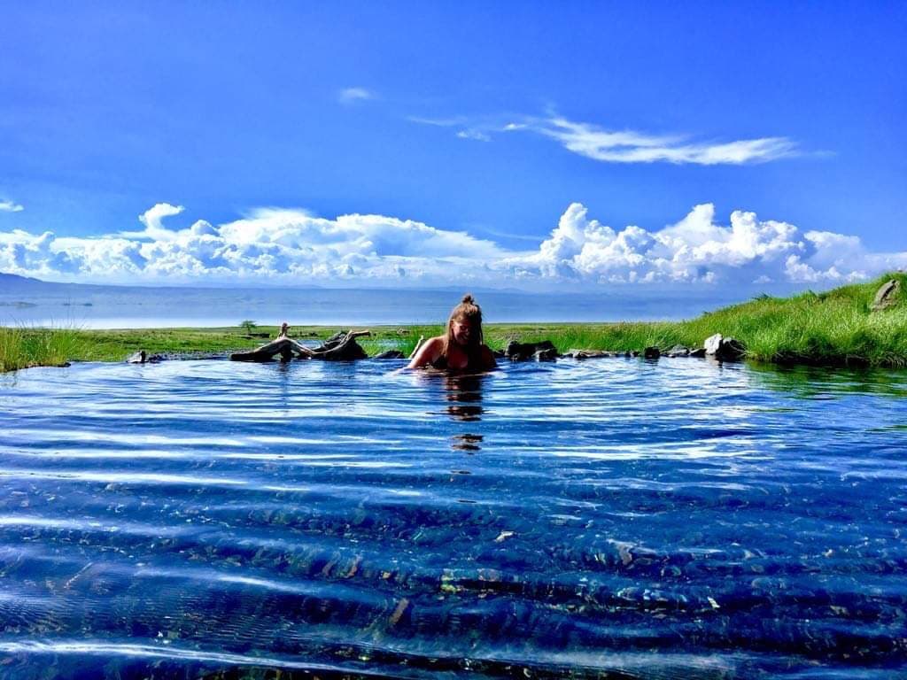 Person soaking in a clear turquoise natural spring pool