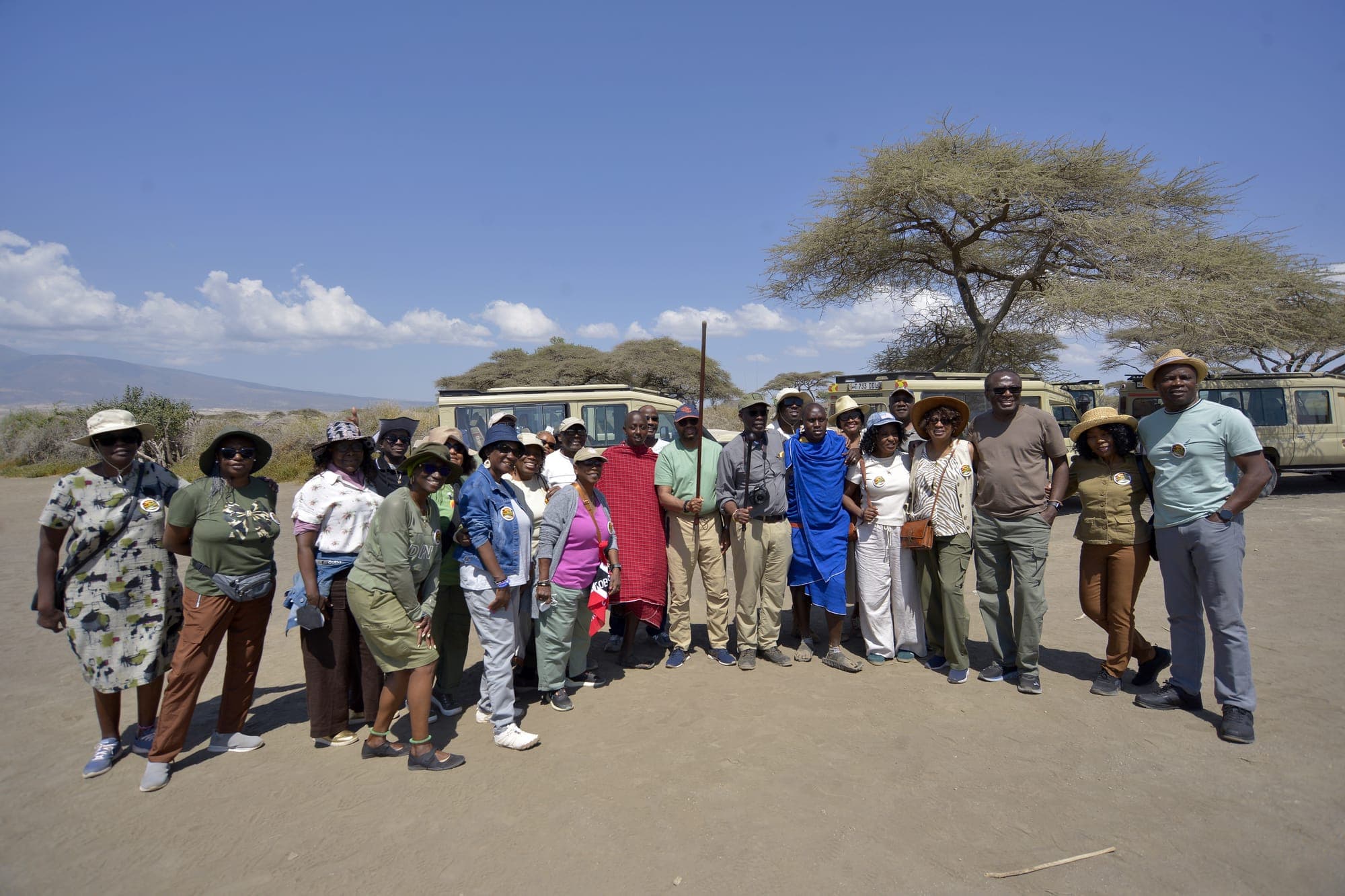 Wide view of a safari vehicle dwarfed by Serengeti's granite kopjes