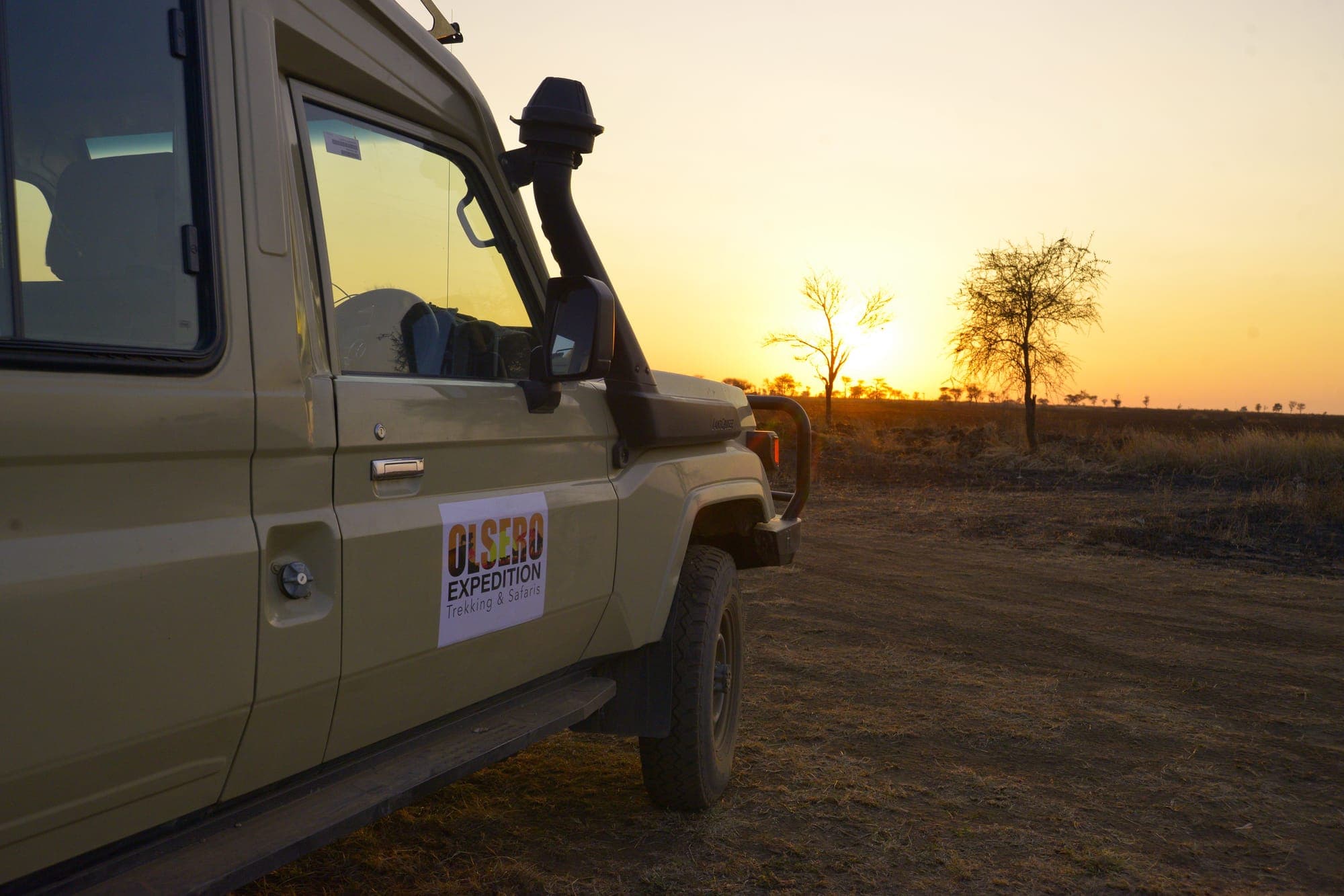 An Olsero Expedition vehicle silhouetted against the setting sun